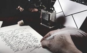 Eine Hand schreibt mit Feder auf ein Blatt Papier.