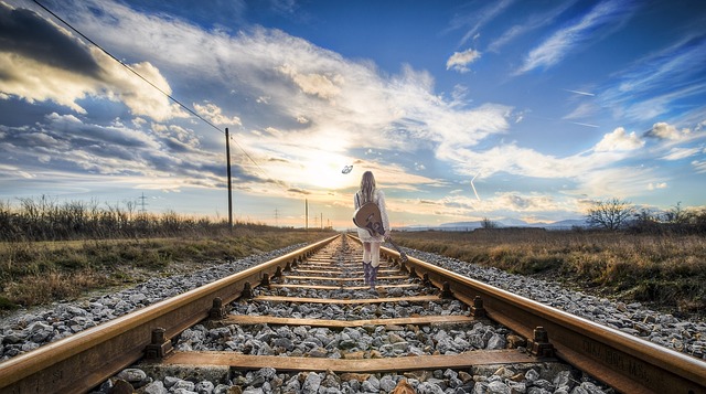 Eine Frau von hinten, die über Bahngleise davonwandert.