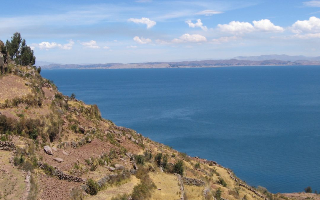 Blick von einer Insel auf den Titicacasee - tiefblaues Wasser, steil abfallendes Ufer